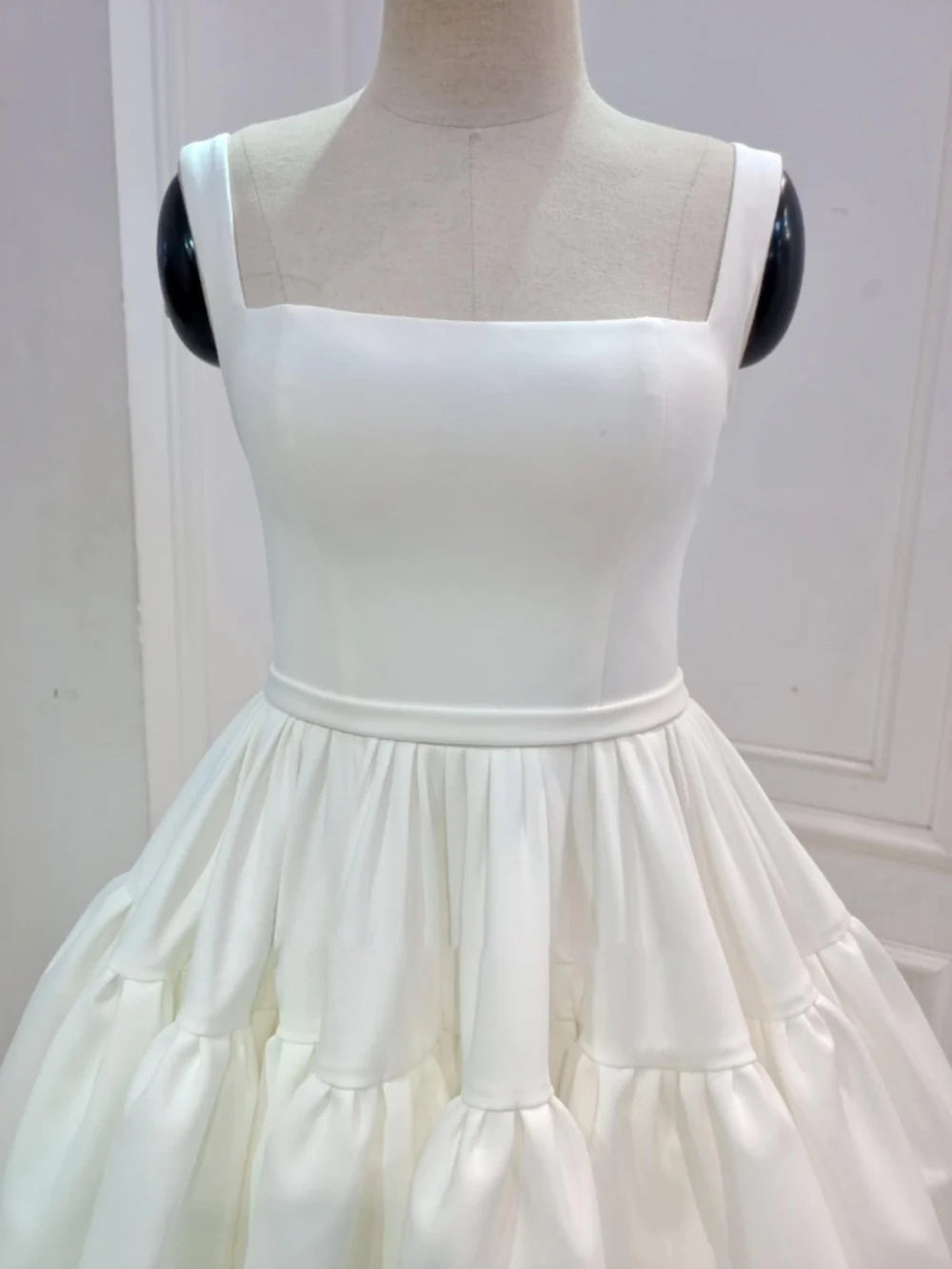 Front view of a model in a chic sweetheart mini wedding dress.