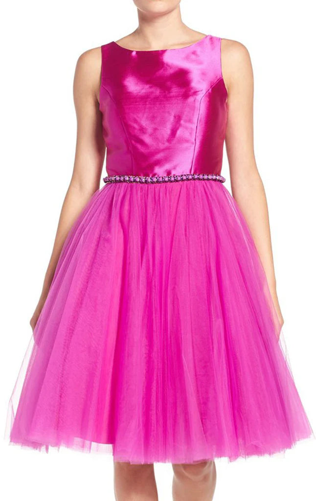 Woman wearing an elegant short tulle prom dress with spaghetti straps.