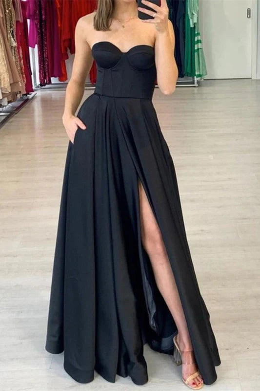 Woman wearing a navy sweetheart prom dress with a high split and pockets.