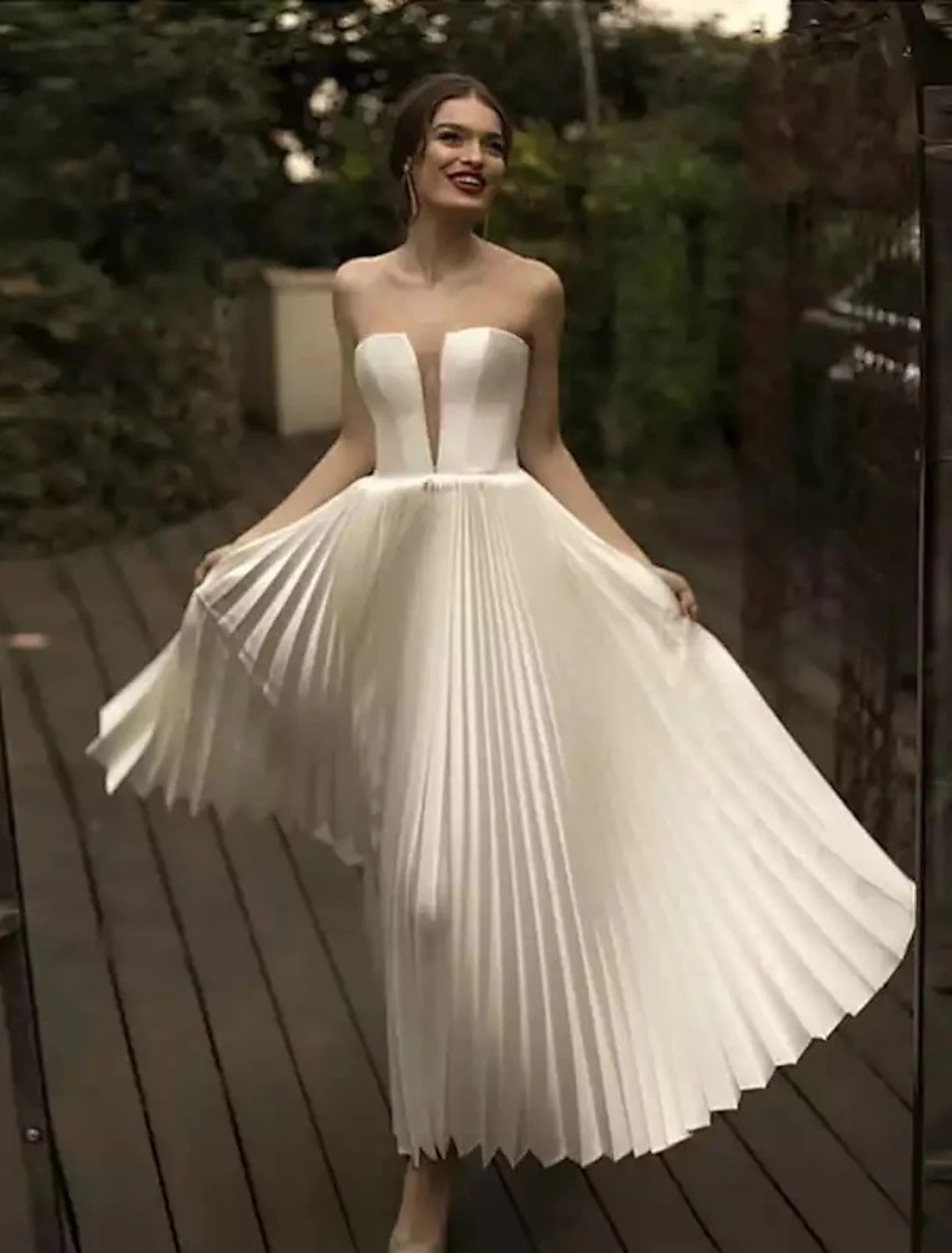 Close-up of white lace and pleated details on an ankle-length wedding dress.