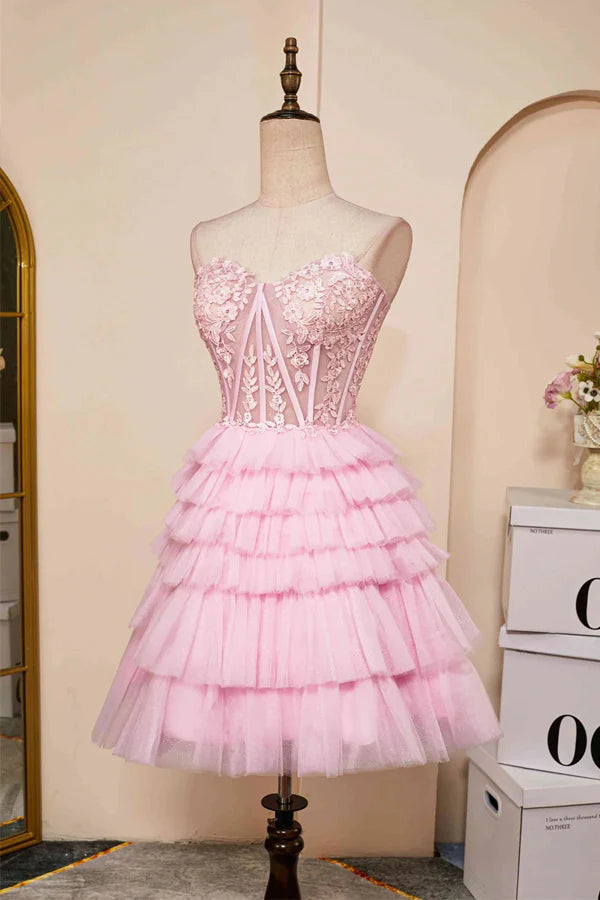 Side profile of a woman wearing a pink strapless layered homecoming dress.