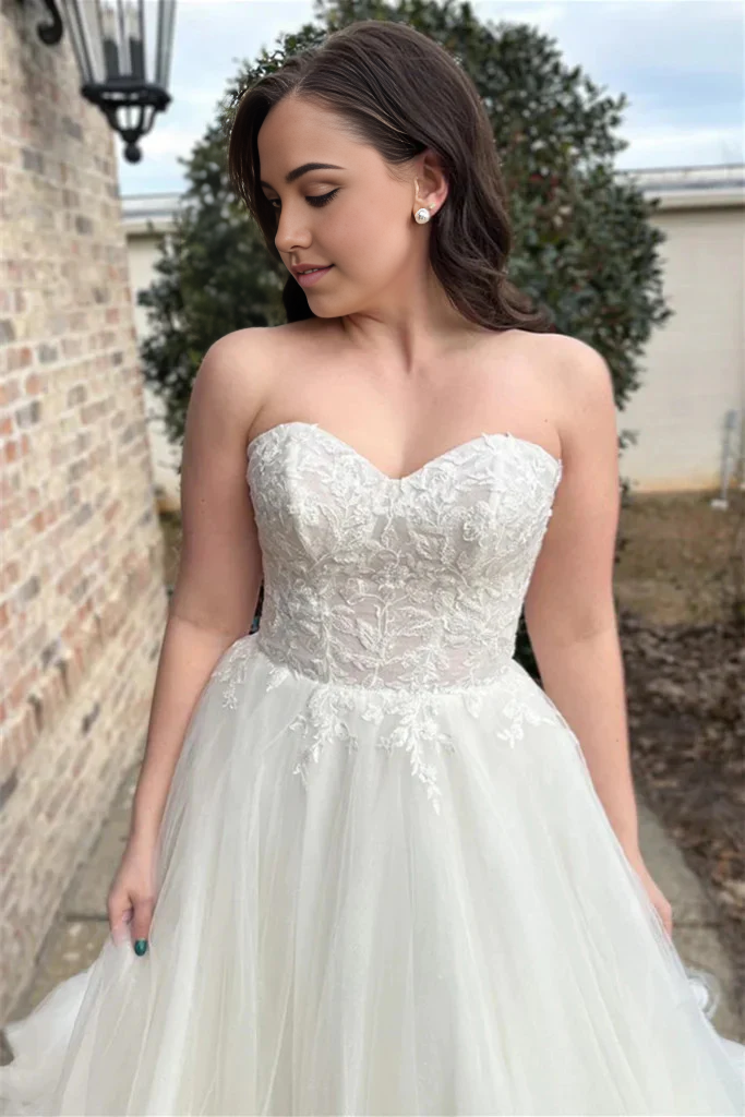 Model wearing an elegant white lace strapless A-line wedding gown.