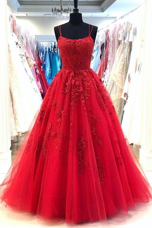 Woman wearing an elegant A-line sweetheart tulle prom dress with lace appliques and spaghetti straps.