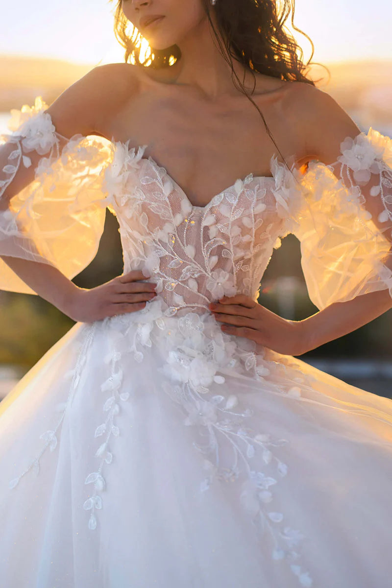 Close-up of the sweetheart neckline and 3D lace appliques on the bodice and long sleeves of the wedding dress.