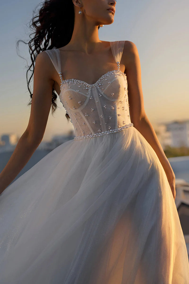 Close-up of the sweetheart neckline and delicate pearl details on the wedding dress.