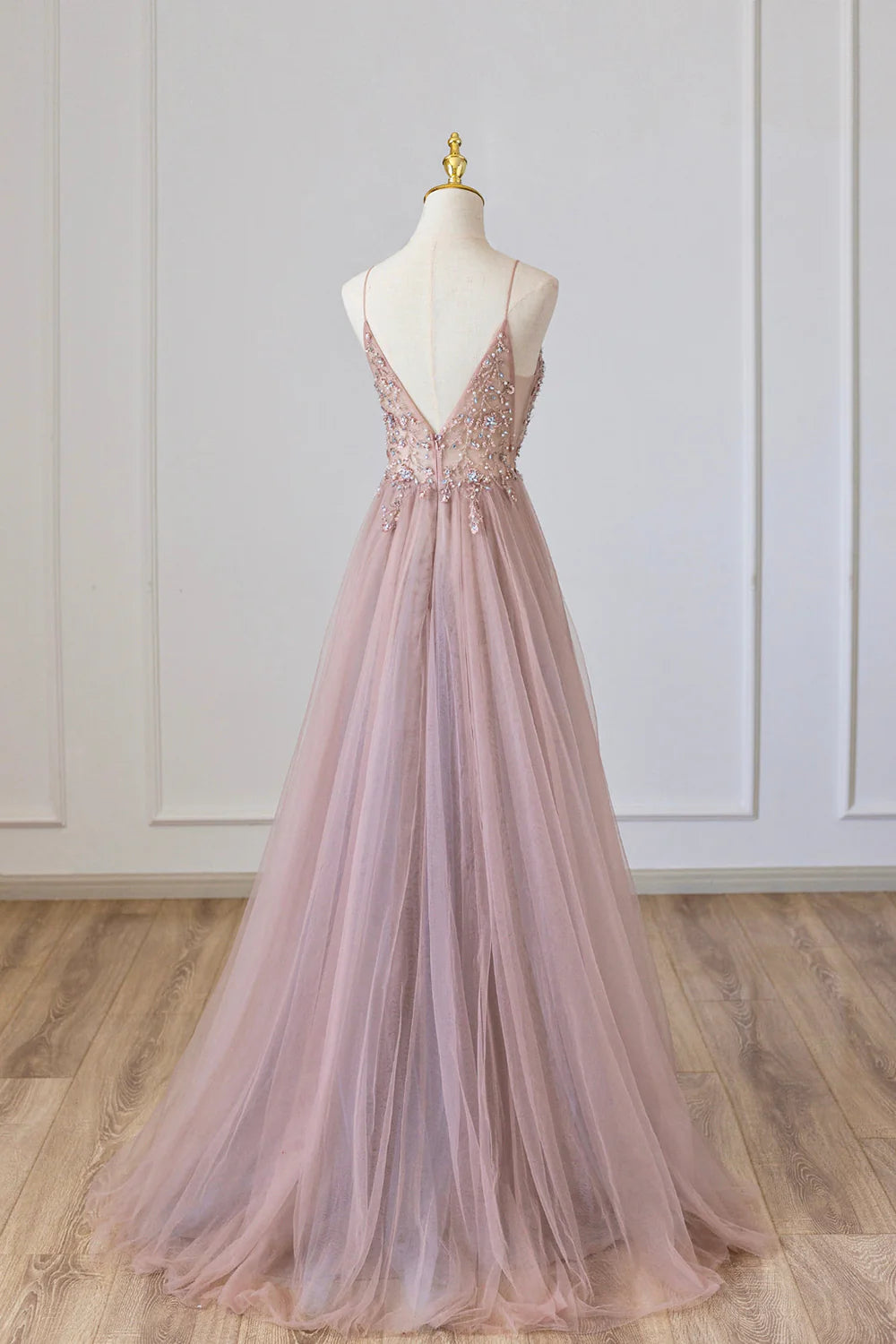 Woman in an A-line tulle long formal dress with spaghetti straps, side profile.