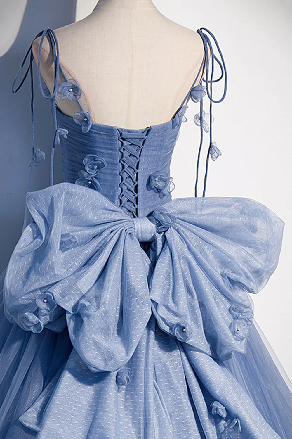 Close-up of the delicate spaghetti straps and flowing tulle fabric of the dress.