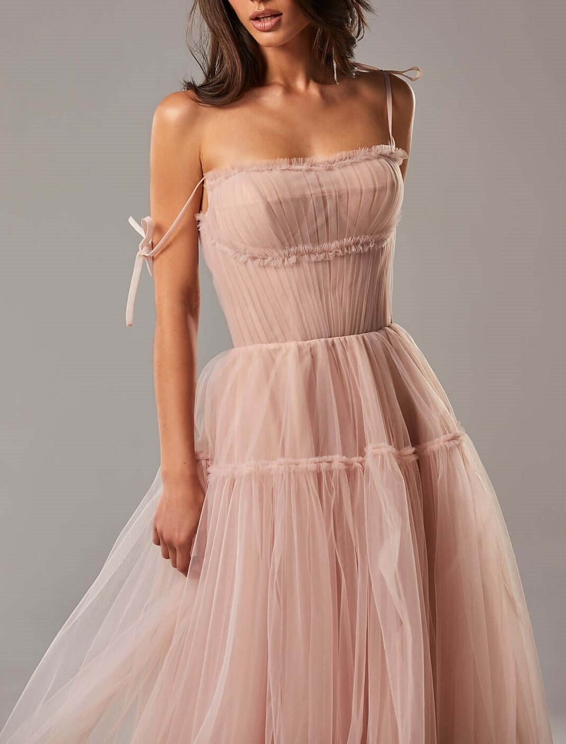 Side profile of a model wearing a formal A-line tulle gown.
