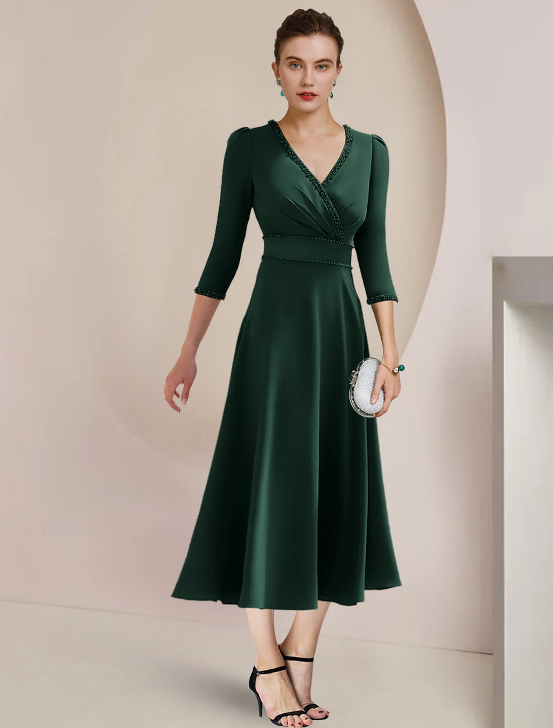 Model wearing an elegant A-line V-neck tea length dress with 3/4 sleeves and beaded side-draping.