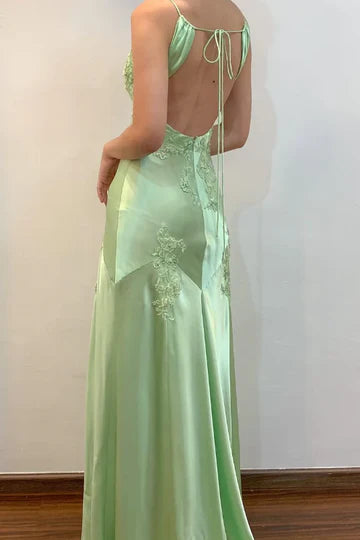Close-up of green satin dress V-neckline with delicate appliques.