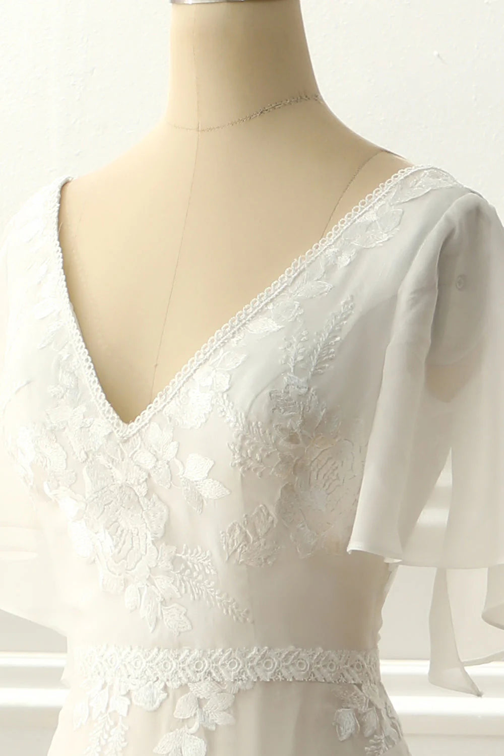 Side profile of the flowing A-line ivory wedding dress with V-neck and appliques.