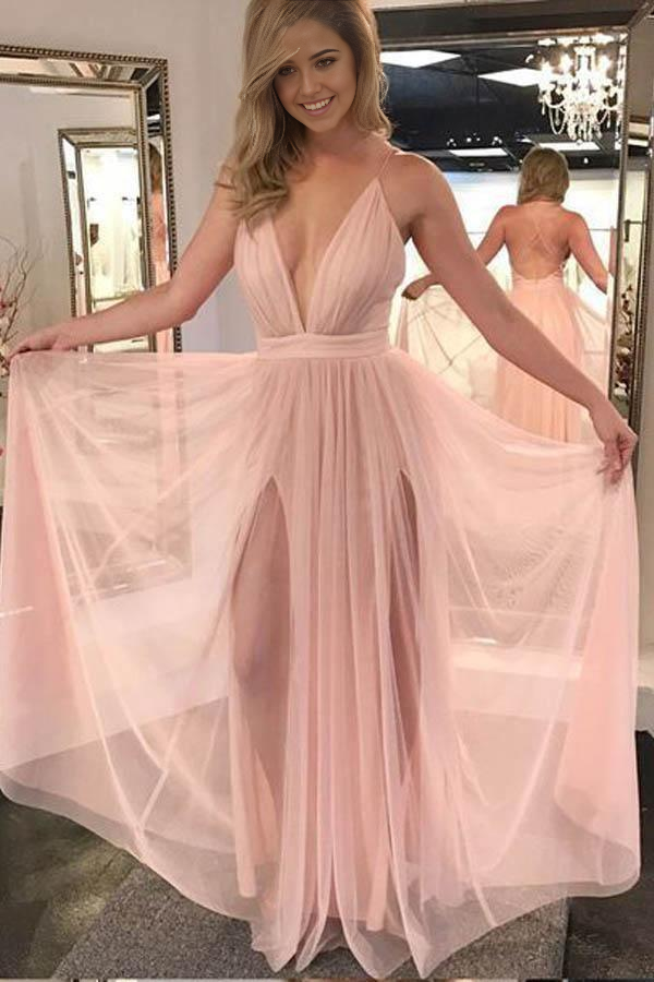 A woman wearing an elegant pink A-line V-neck backless chiffon long prom dress with a high slit.