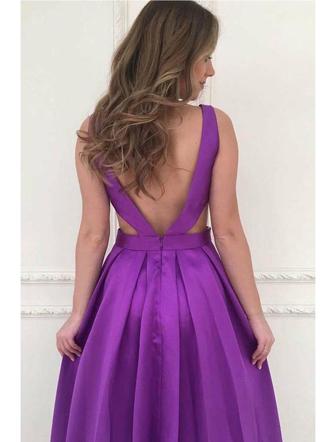 Back view of a floor-length A-line prom dress showing the V-back and pleats.
