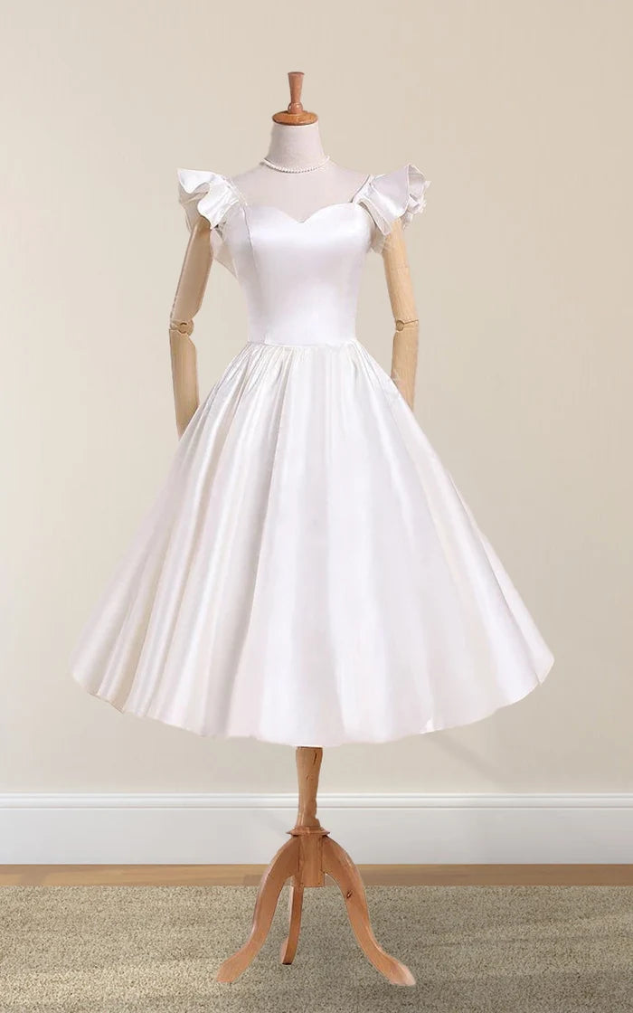 Model wearing a white tea-length satin wedding dress with bell sleeves and pleated skirt.