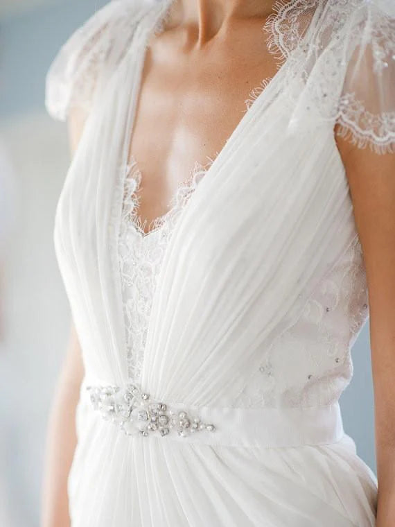 Elegant A-line V-neck lace wedding dress with cap sleeves.