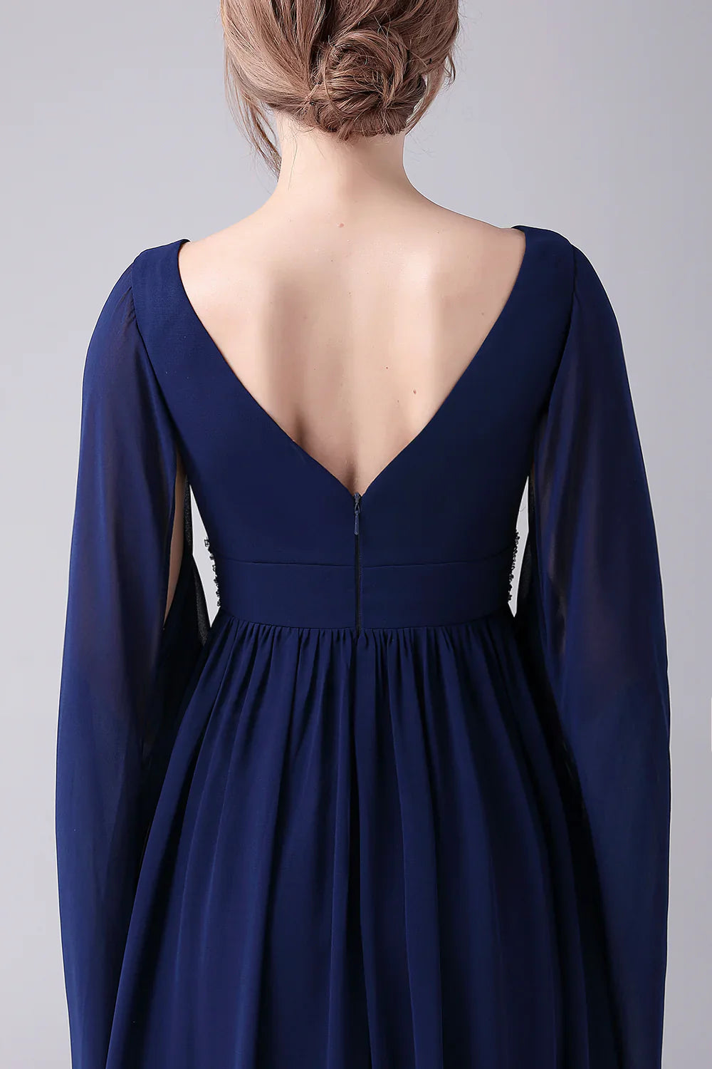 Detailed view of the flowing skirt and pleated fabric of the floor-length dress.
