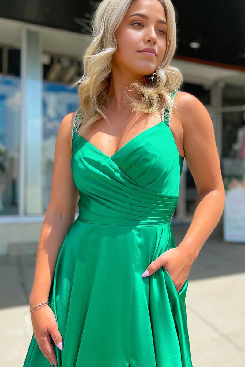 Side profile of a woman wearing a green satin V-neck prom dress, highlighting the silhouette.