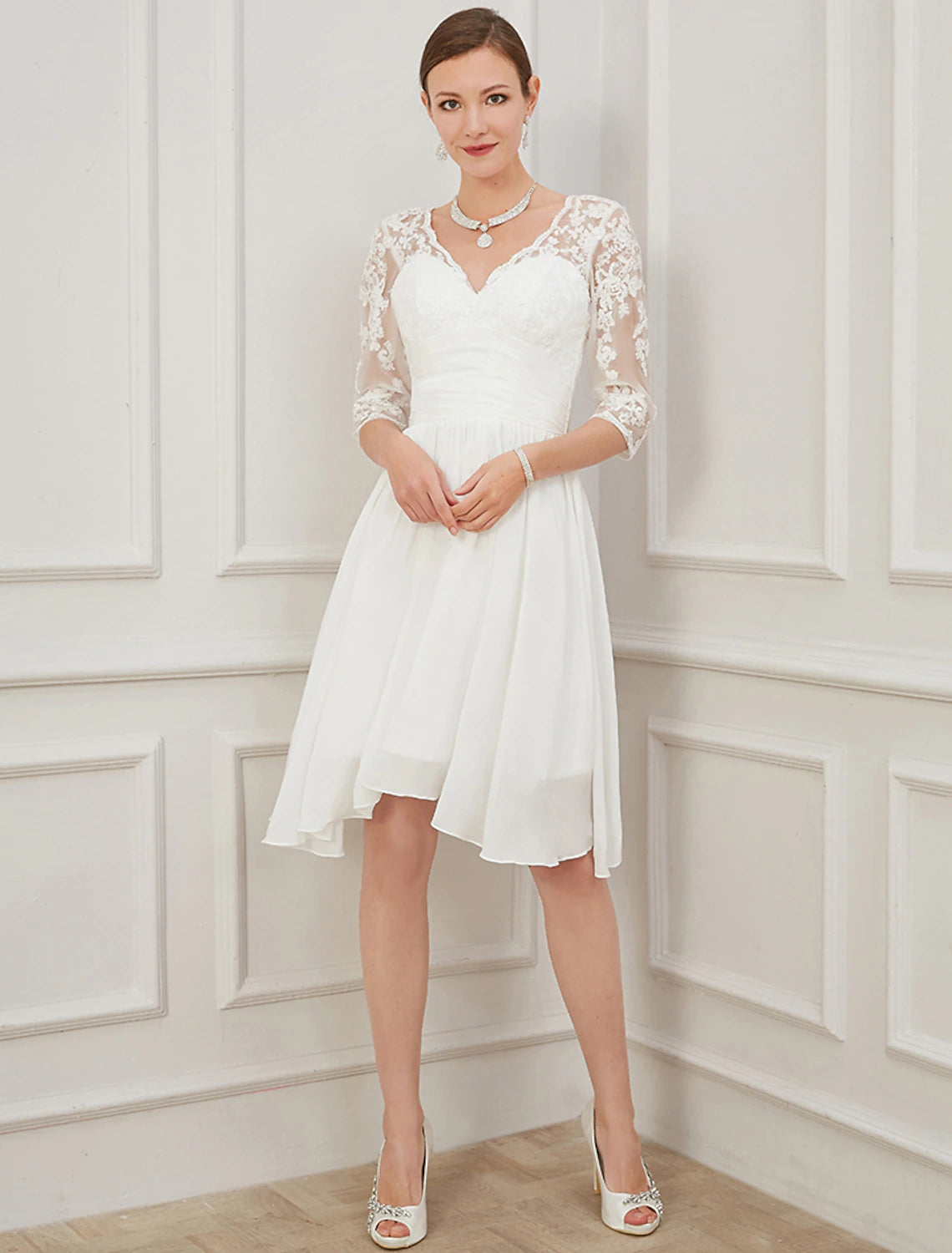 Model wearing an elegant white A-line knee-length dress with V-neck and half sleeves.