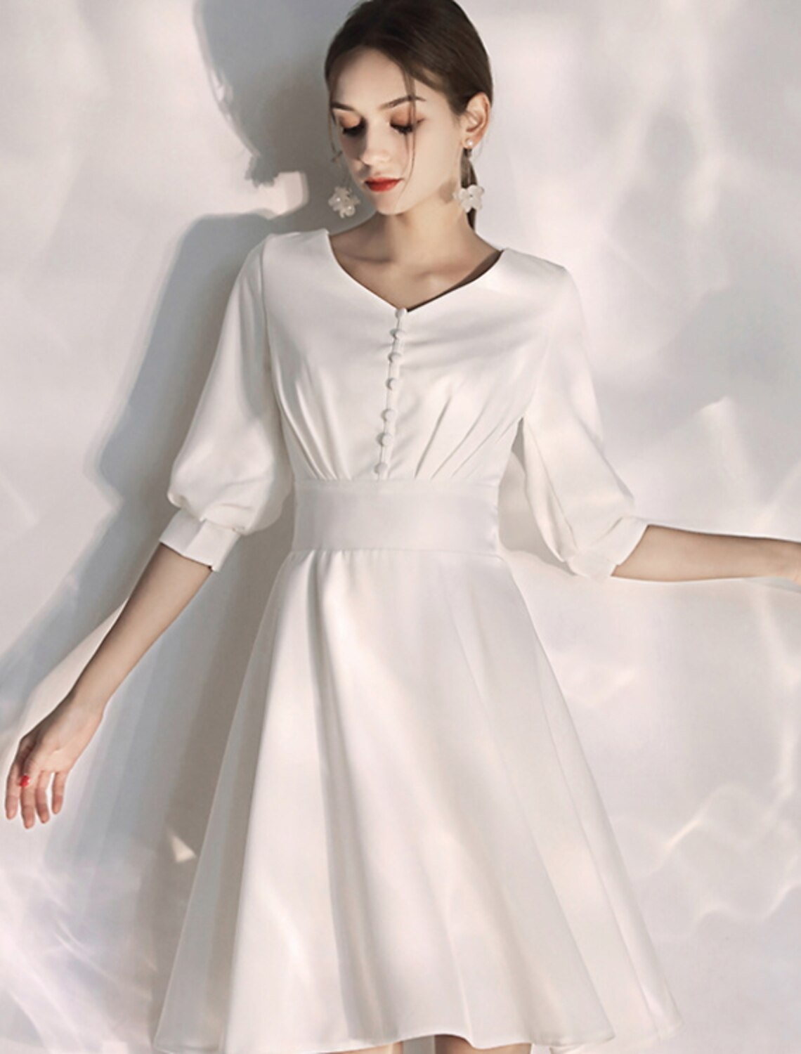 Close-up of the V-neckline and half sleeves on the white stretch fabric wedding dress.