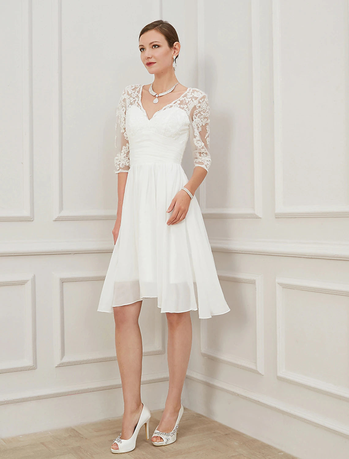 Side view of the white chiffon knee-length bridal gown with draping details.