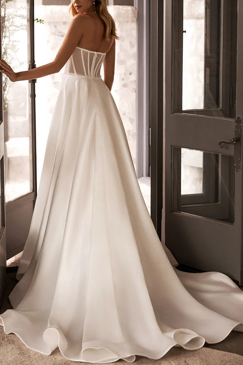 Back view of a woman in a white A-line satin wedding dress.