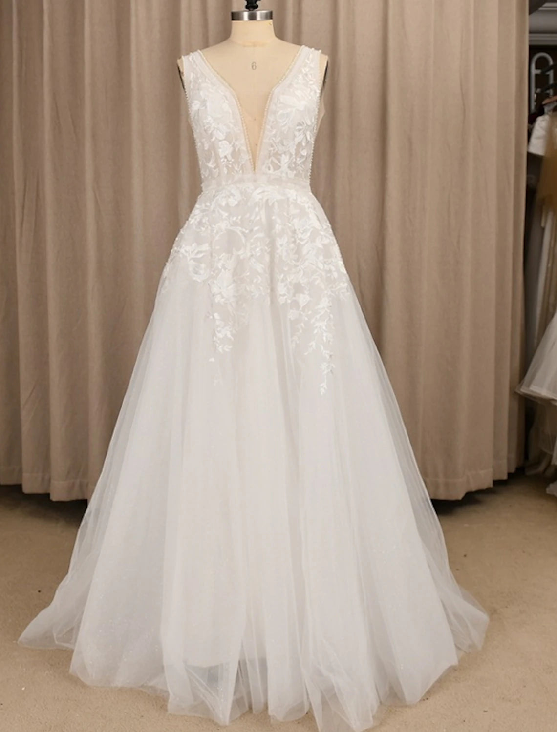 Full view of an A-line V-neck lace wedding dress with a sweep train.