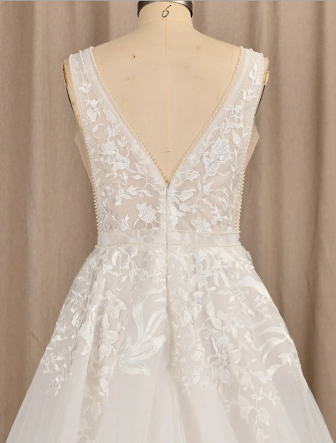 Side view of an A-line V-neck lace wedding dress, showing appliques.