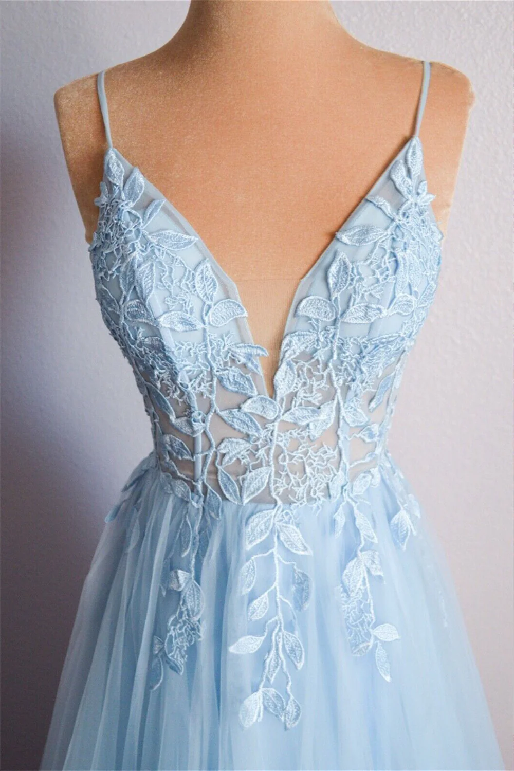Side view of a V-neck formal gown with intricate appliques on tulle fabric.