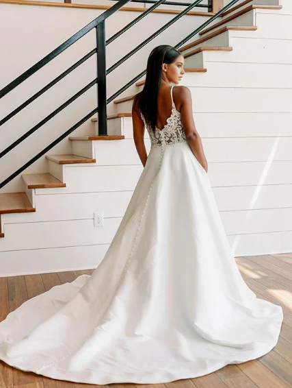 Close-up detail of the lace and V-neckline on a white formal dress.