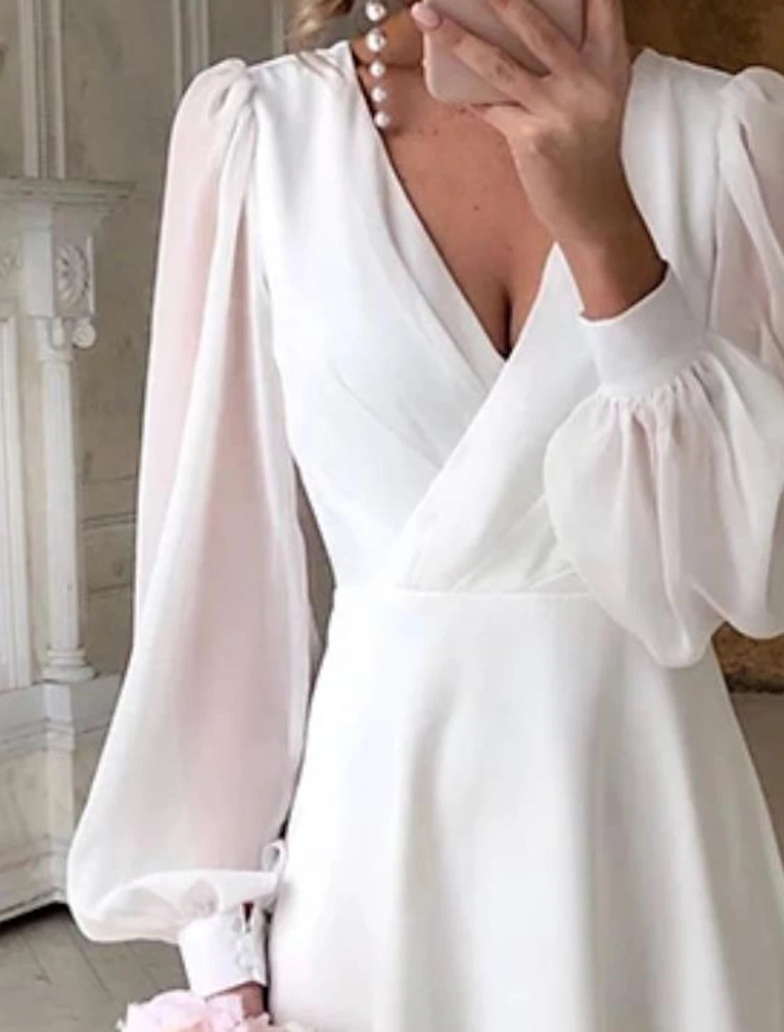 Close-up of the V-neckline and long sleeves on the white chiffon gown.