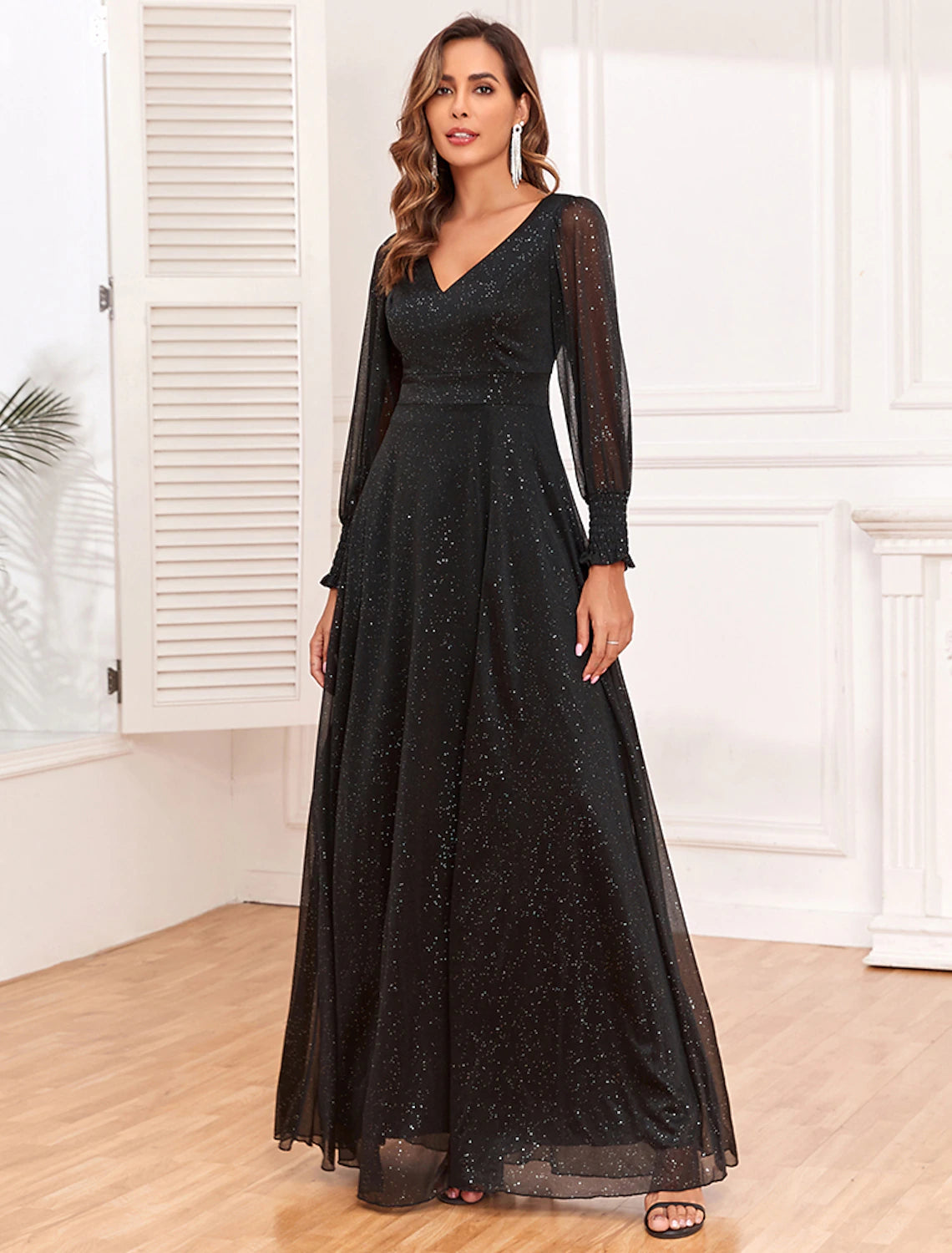 Model wearing an elegant black A-line V-neck long sleeve evening gown with glitter and a high slit.