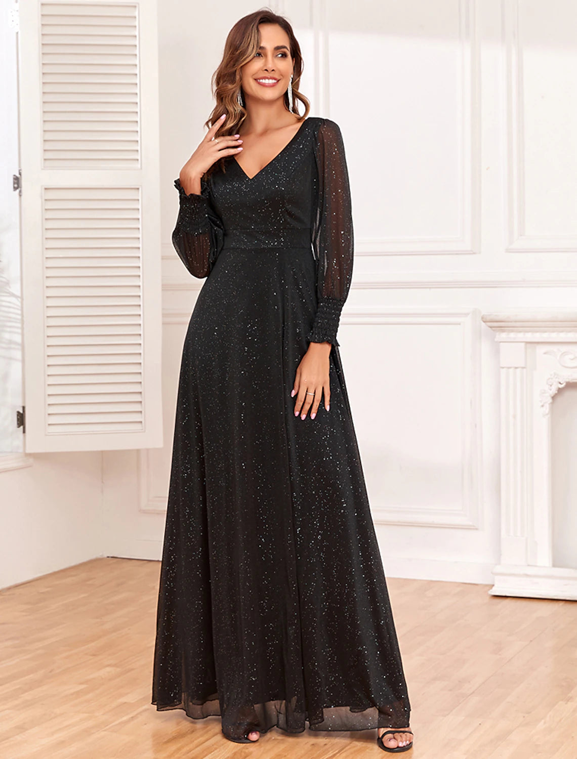 Detailed view of the V-neckline and empire waist of the black evening dress.
