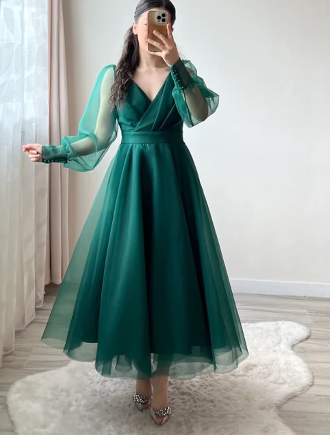 Woman wearing an elegant A-line V-neck long sleeve organza tea length cocktail dress.