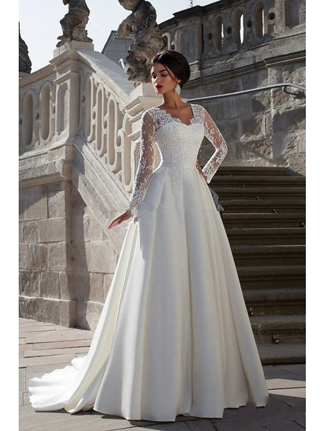 Close-up of the V-neck bodice and long sleeves of the satin wedding dress with appliques.