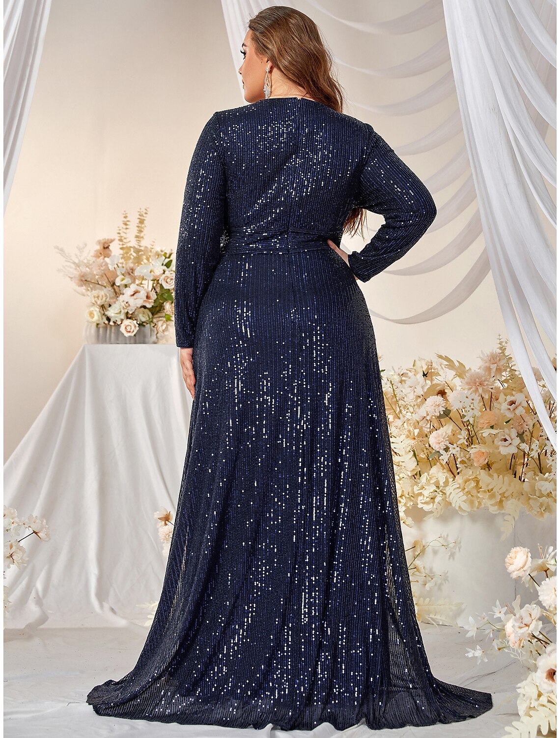 Woman posing in a long sleeve V-neck plus size formal gown.