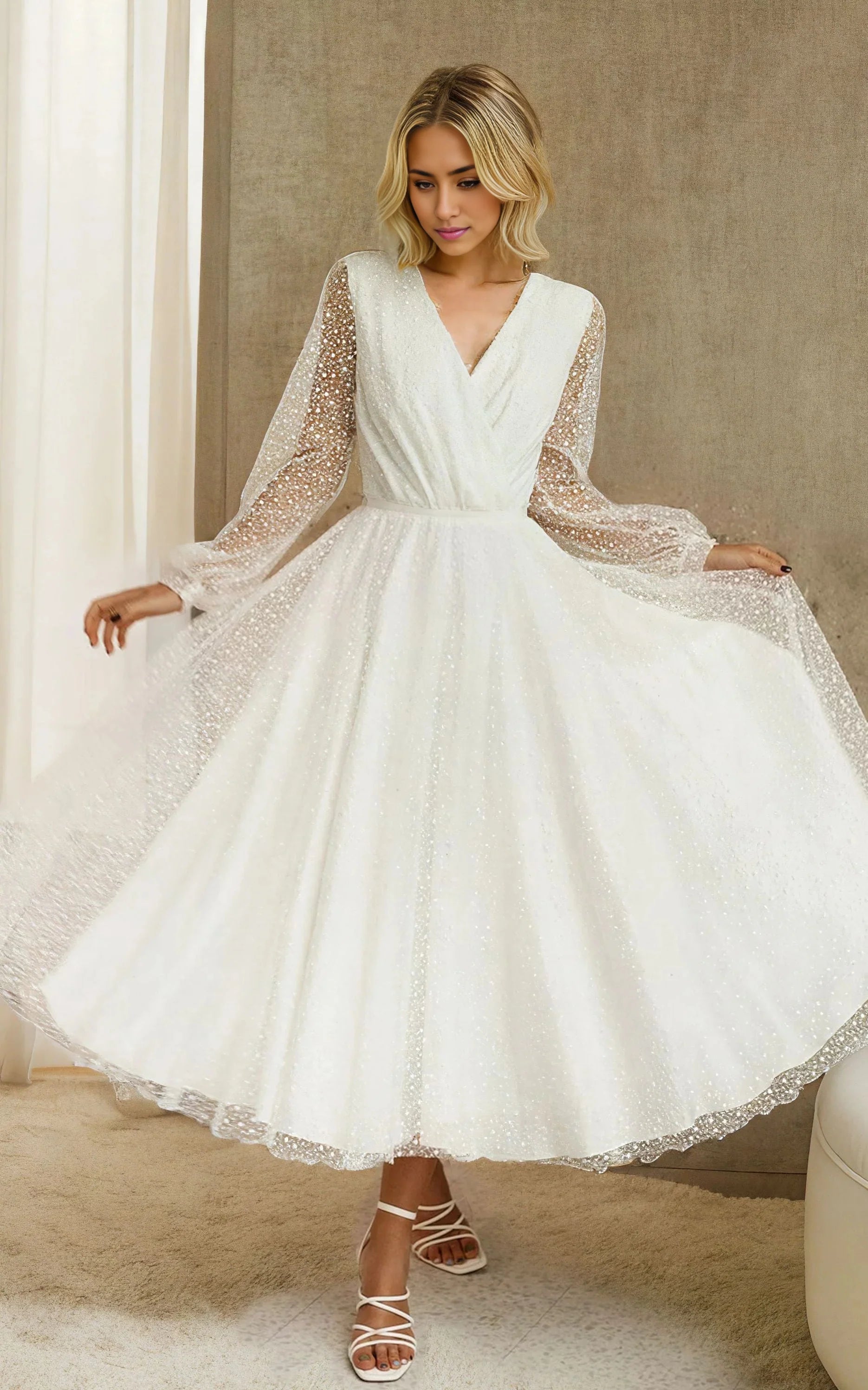 Woman wearing a white A-line tulle tea-length wedding dress with long sleeves and V-neck.