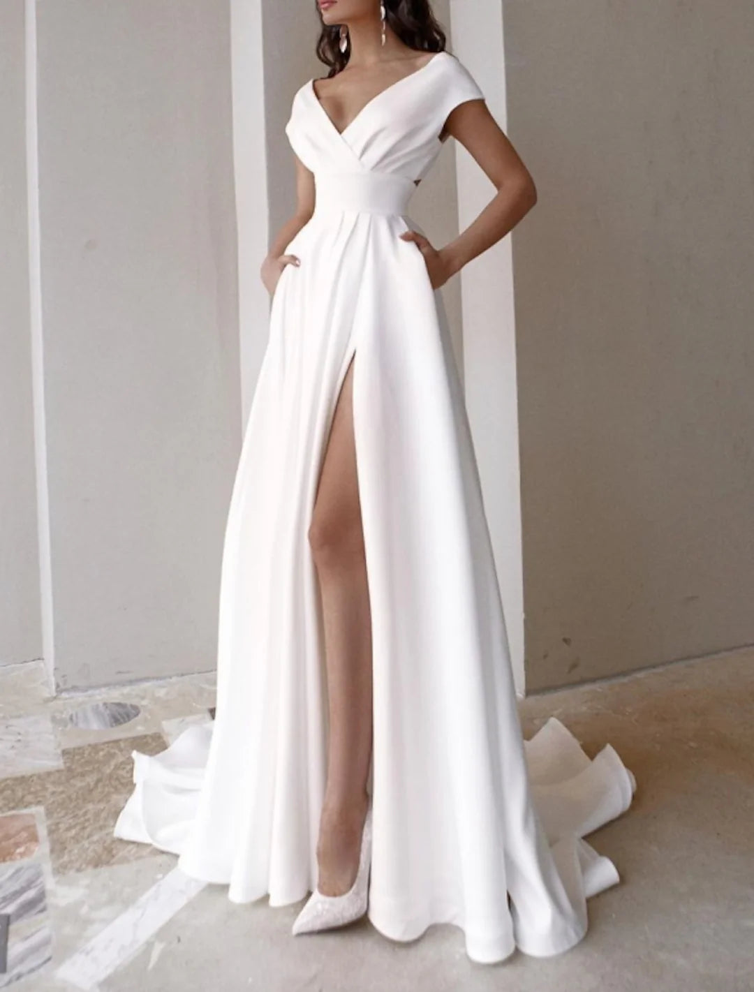 Elegant A-line V-neck long sleeve wedding dress with a flowing train on a model.
