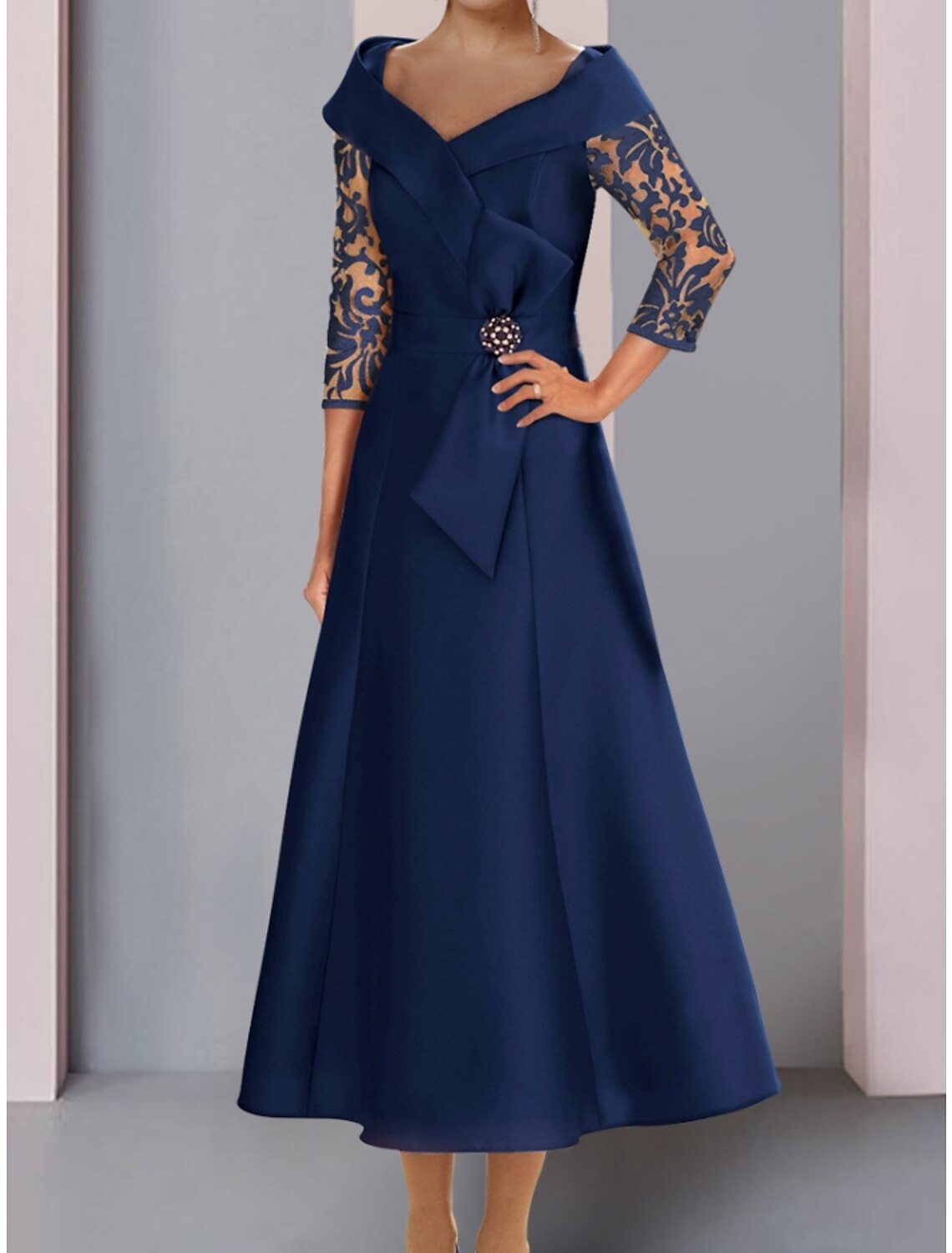Tea length satin and lace wedding guest dress with bow and ruching details.