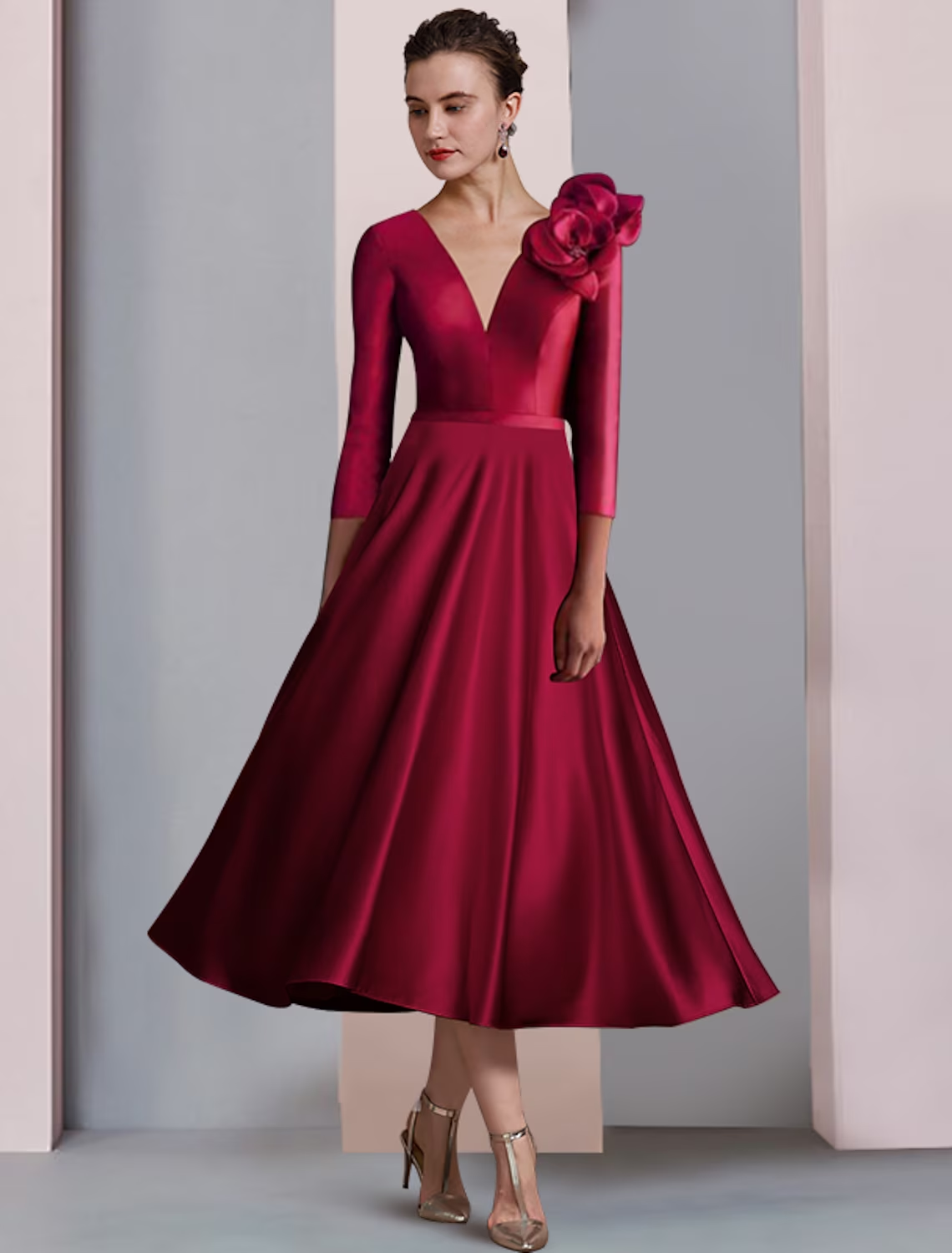 Elegant A-line satin V-neck tea length dress with 3/4 sleeves and pleats, worn by a woman.