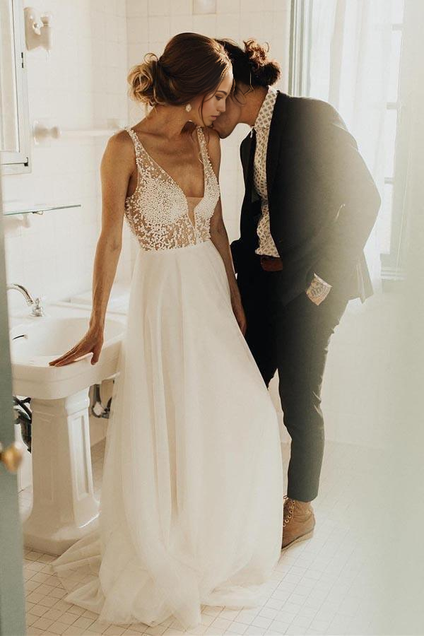 Model wearing an elegant ivory A-line V-neck wedding dress with pearl beading.