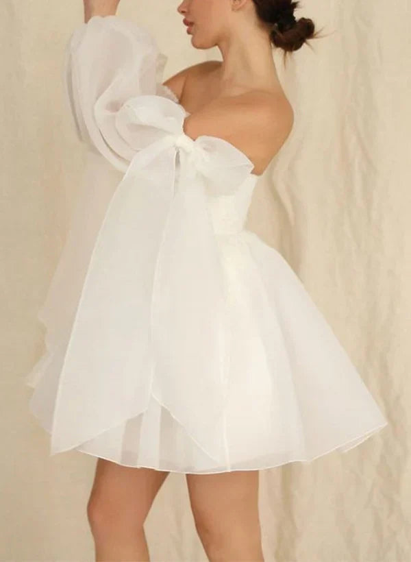 Close-up of the V-neckline, puff long sleeves, and delicate bow on the wedding dress.