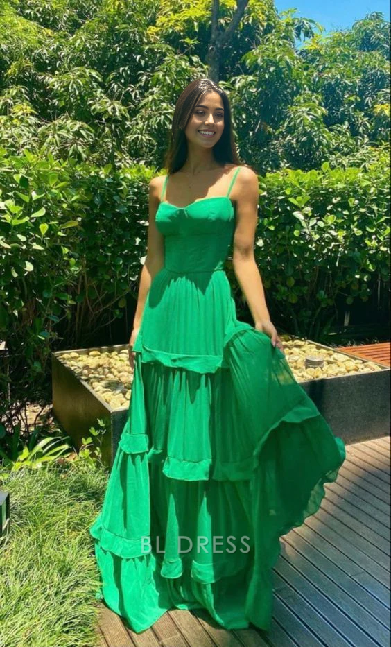 Woman wearing an elegant green A-line formal dress with spaghetti straps and ruffle detail.