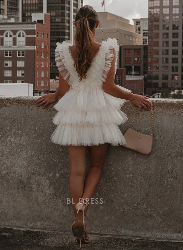 Back view of a model in a white A-line V-neck ruffled tiered mini dress.