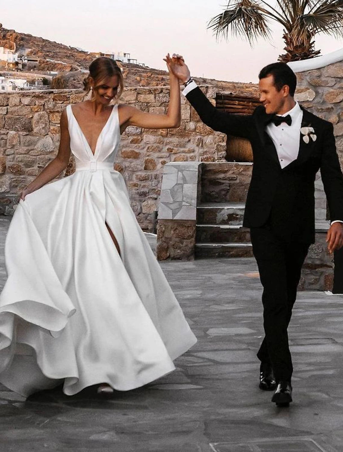 A-line V-neck satin wedding dress with a court train and sashes, front view.