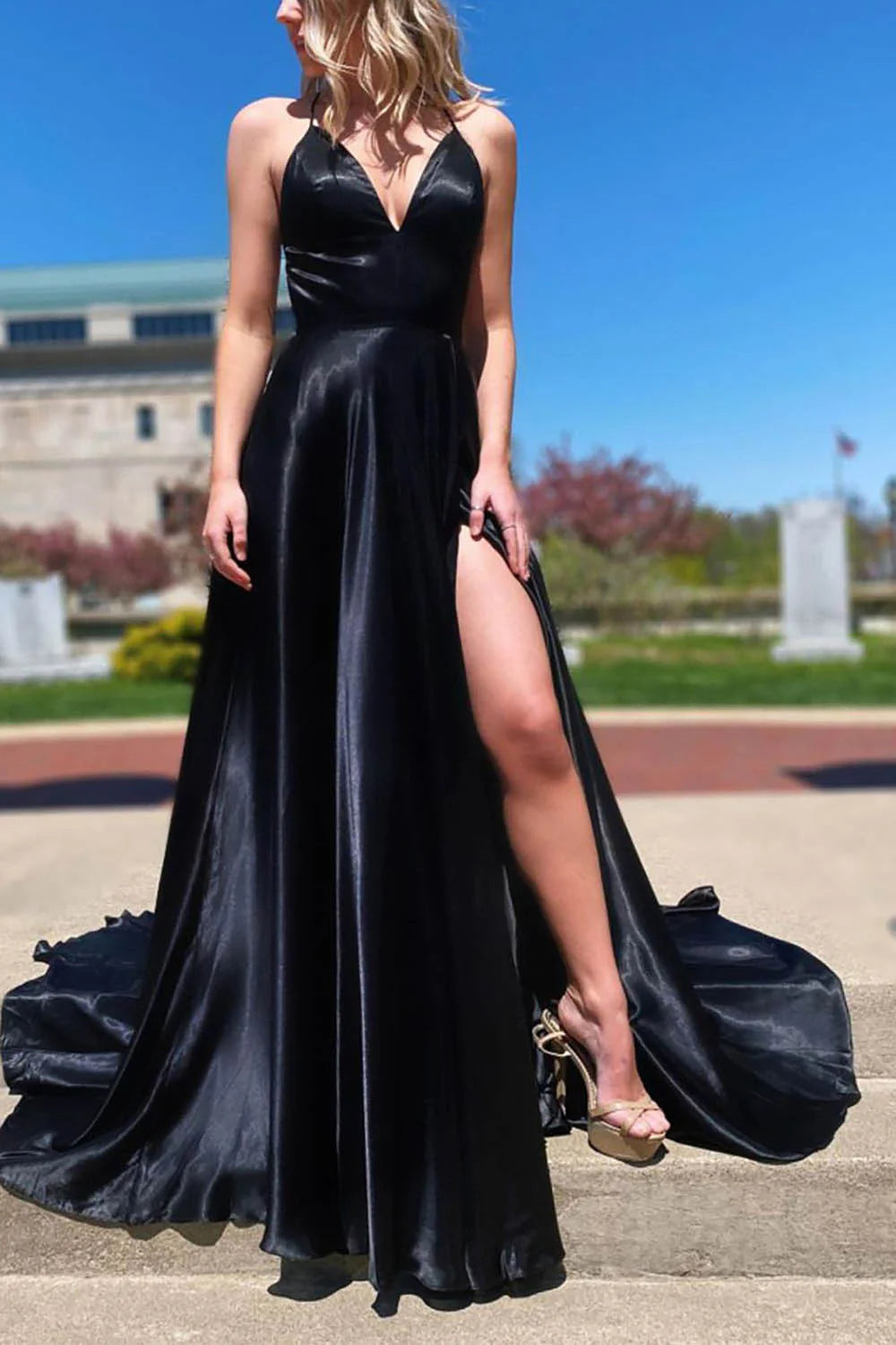Woman wearing an elegant A-line V-neck satin long prom dress with a high slit.