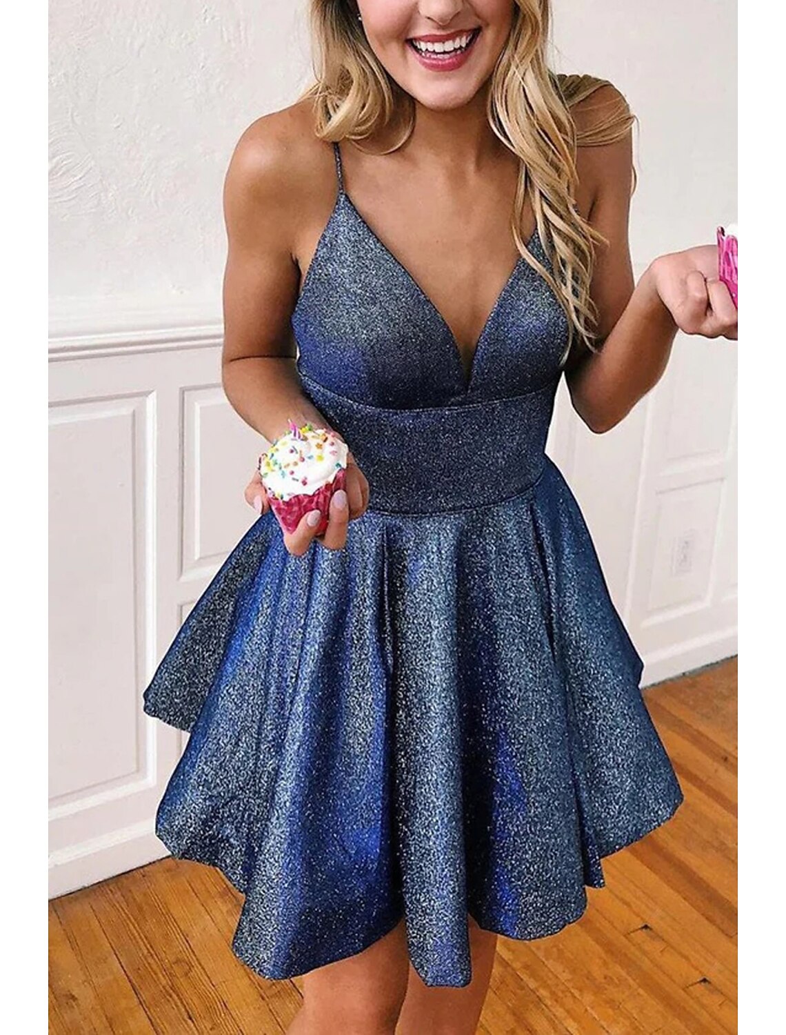 Side view of a model in a sleeveless A-line satin party dress with pleats.