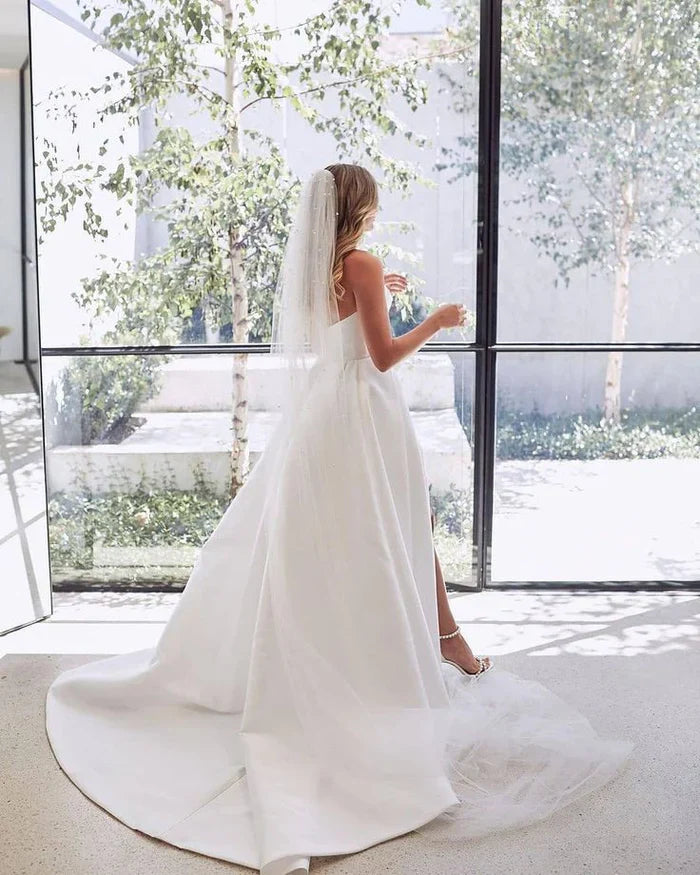 White A-Line sleeveless satin wedding gown with a high side slit.