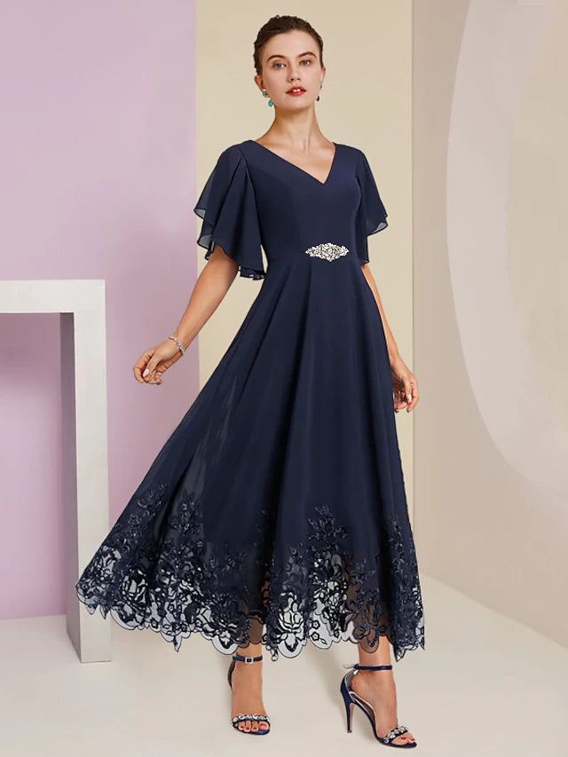 Woman wearing an elegant A-line V-neck tea length chiffon lace dress with appliques and a crystal brooch.