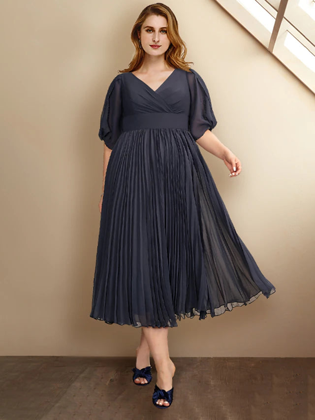 Woman wearing an elegant A-line V-neck short sleeve tea-length chiffon dress with pleats.