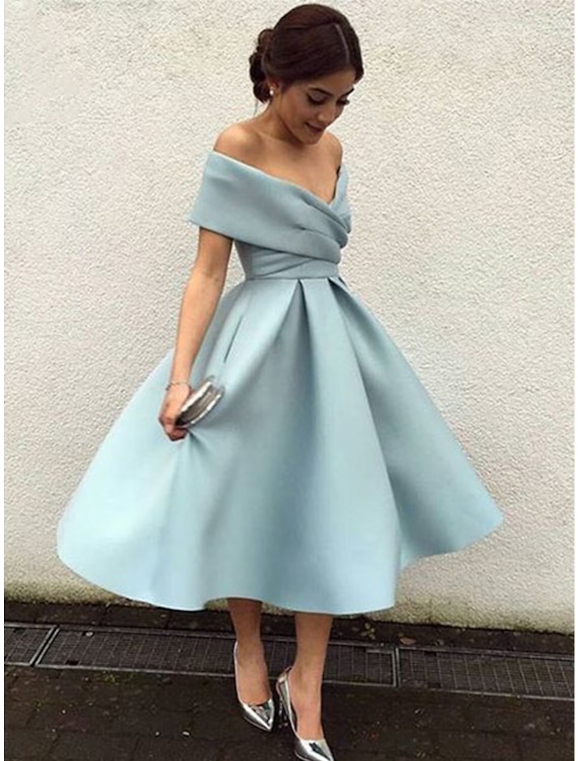 Woman wearing an A-line V-neck short sleeve tea length dress with pleats.